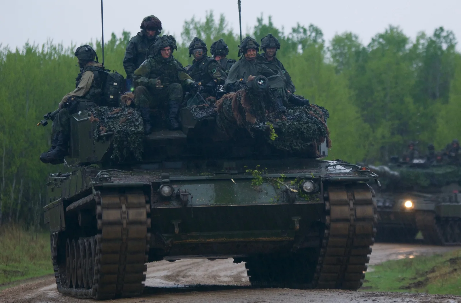 Canadian soldiers ride a camouflaged Leopard 2A4 tank during Exercise Maple Resolve at Wainwright in 2017.