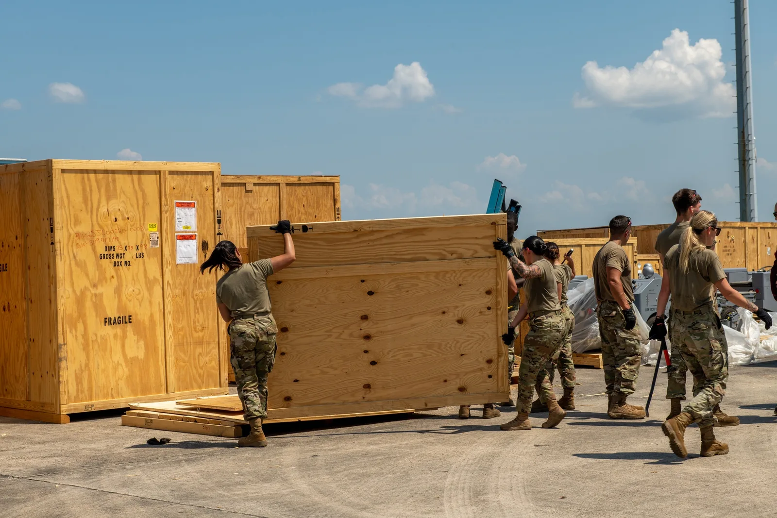 U.S. Air Force personnel remove wooden crate panels during the arrival of F-35A support equipment at Tyndall Air Force Base.