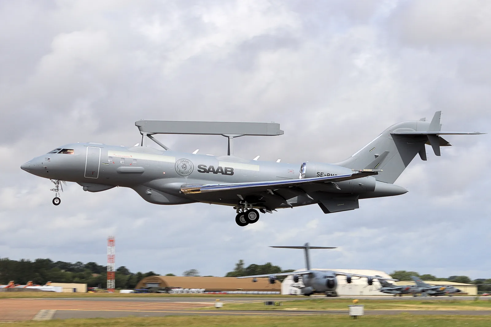 Saab GlobalEye SE-RMS approaches a runway with its landing gear extended and radar mounted above the fuselage.